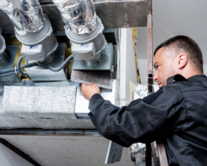 Man on a ladder, changing an air filter from a vent